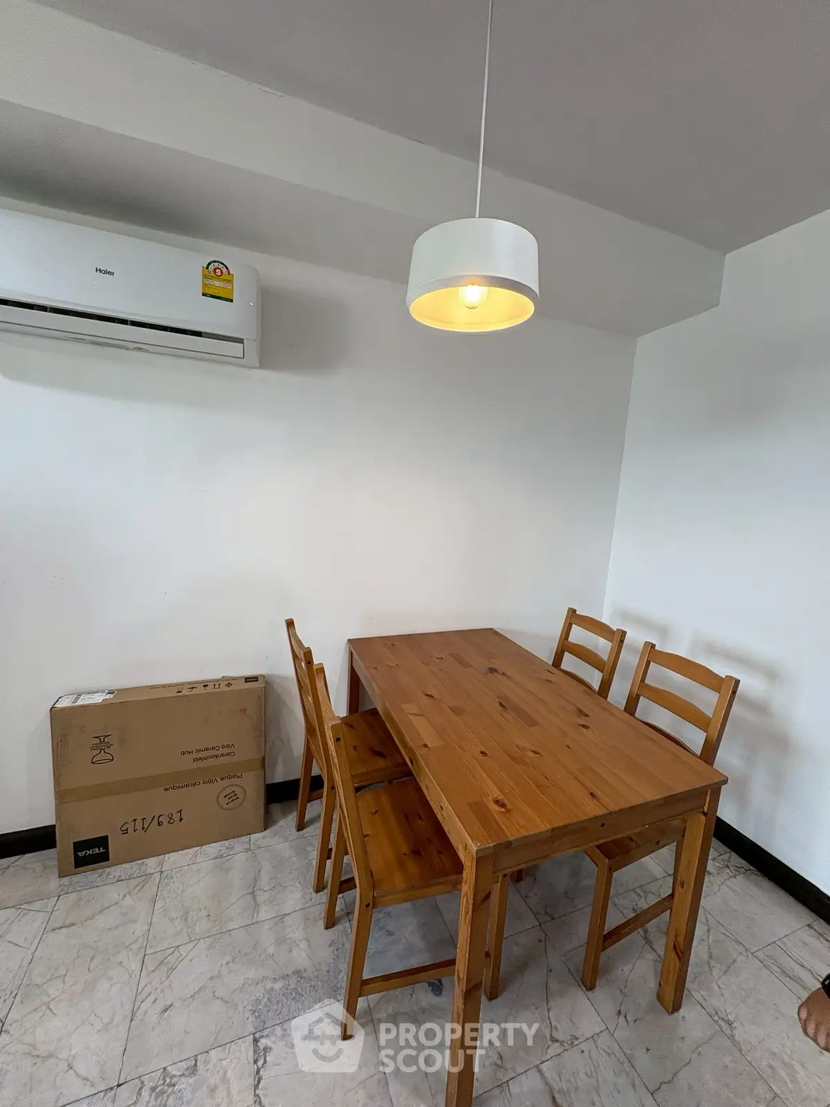 Cozy dining area with wooden table and chairs, featuring a modern pendant light and air conditioning.