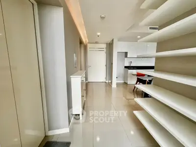 Modern open-plan kitchen with sleek white cabinetry and glossy tiled flooring.