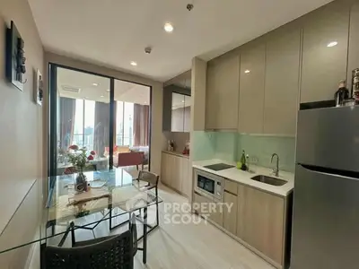 Modern kitchen with sleek cabinetry and glass dining table, open layout to living area.