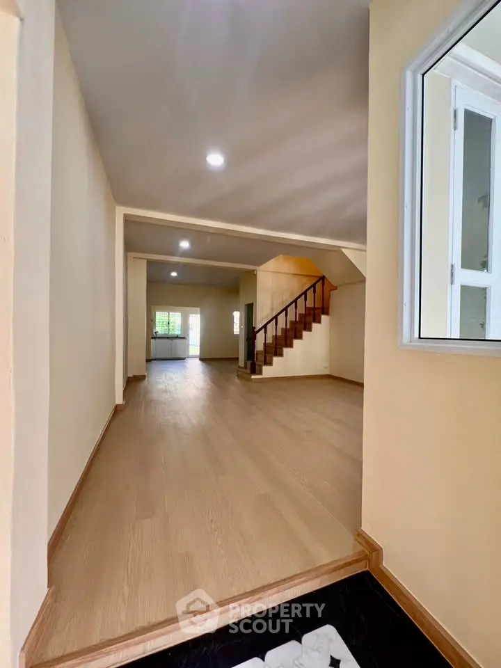 Spacious open-plan living area with wooden flooring and staircase, perfect for modern family living.