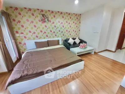 Charming bedroom with floral accent wall and cozy seating area, perfect for relaxation.