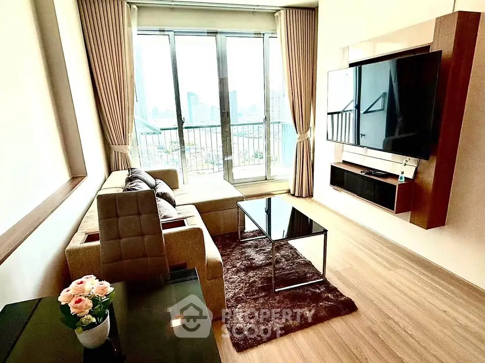 Modern living room with large TV and city view balcony in high-rise apartment.