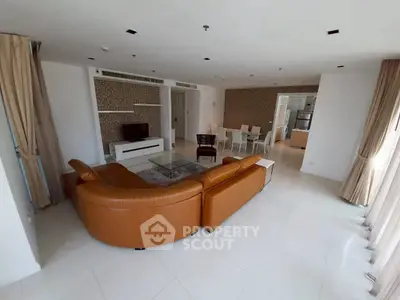 Spacious modern living room with leather sofa and dining area, perfect for family gatherings.