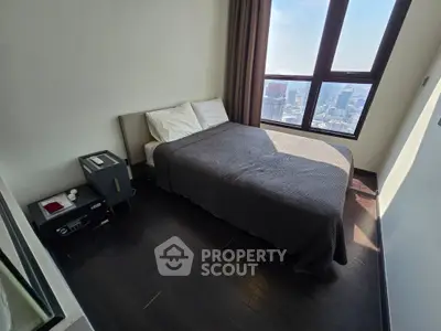 Cozy bedroom with city view, featuring a comfortable bed and large window for natural light.