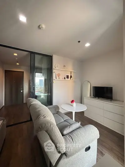 Modern living room with cozy gray sofa and sleek white furniture