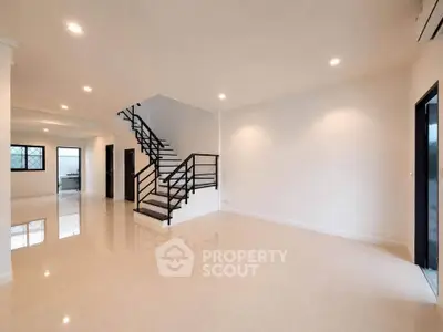 Spacious modern living room with sleek staircase and glossy tiled floors