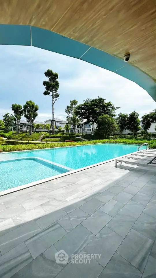 Luxurious outdoor pool with serene garden view in upscale residential area.