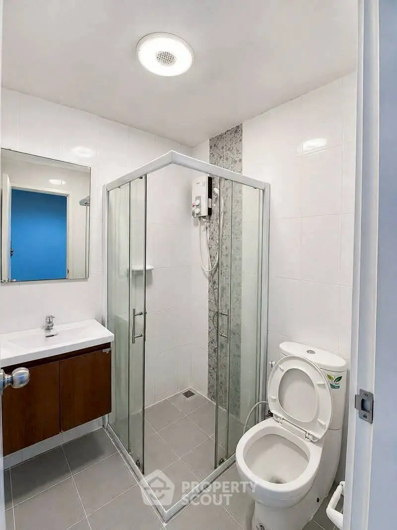 Modern bathroom with glass shower, sleek vanity, and toilet in a contemporary apartment.