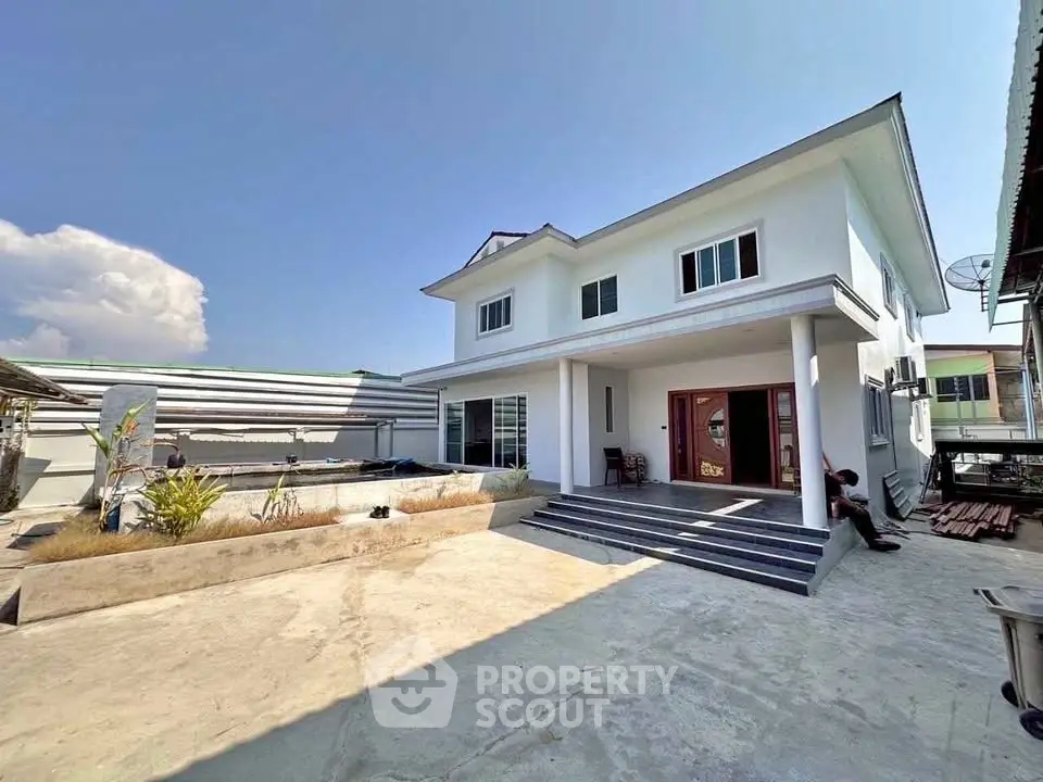 Spacious modern two-story house with large front yard and clear blue sky.