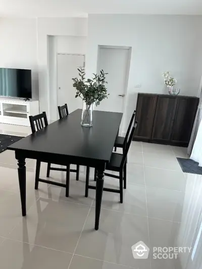 Modern dining area with sleek black table and chairs, elegant decor, and glossy tiled flooring.