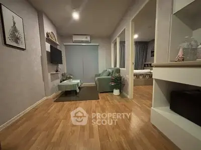 Cozy living room with modern decor and wooden flooring, featuring a comfortable sofa and wall-mounted TV.