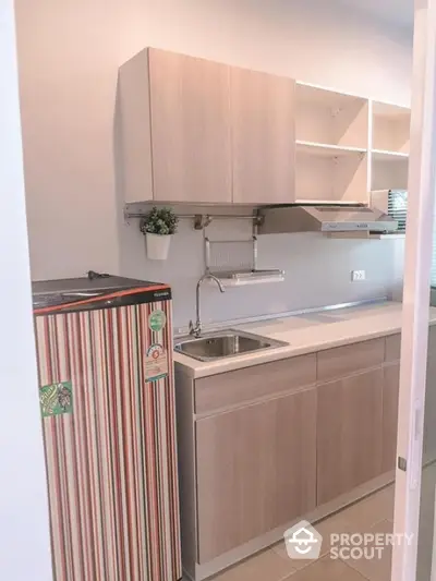 Modern compact kitchen with sleek cabinets and striped fridge