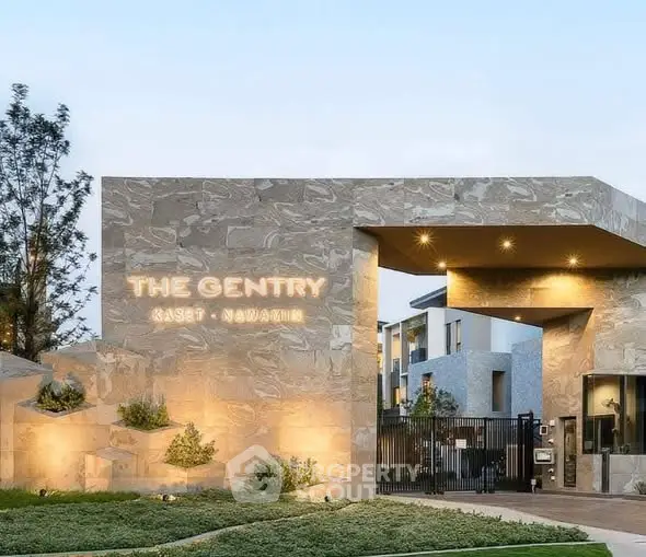 Modern gated entrance of luxury residential complex with stylish stone facade.