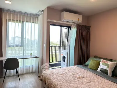 Modern bedroom with balcony view, featuring a cozy bed, desk, and air conditioning.