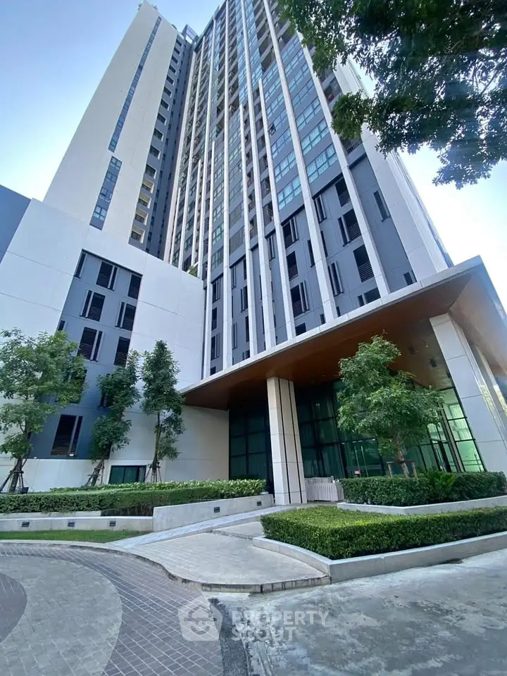 Modern high-rise building with sleek architecture and lush landscaping, showcasing urban living at its finest.