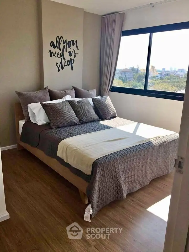 Cozy bedroom with large window and stylish decor in modern apartment.