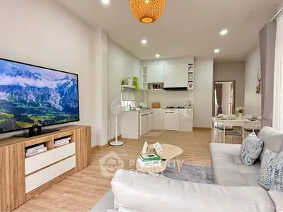 Modern living room with open kitchen, stylish decor, and cozy seating area.