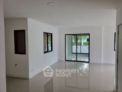 Spacious modern living room with large windows and glossy tile flooring.
