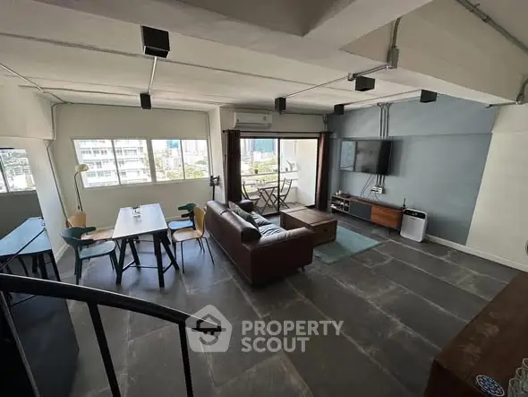 Spacious modern living room with stylish furniture and large windows offering city views.