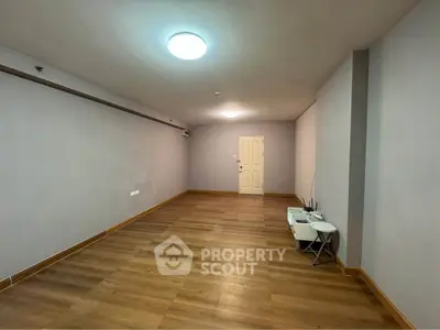 Spacious empty room with wooden flooring and modern lighting, ideal for customization.