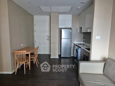 Modern apartment interior with compact kitchen and dining area, featuring sleek appliances and contemporary furniture.