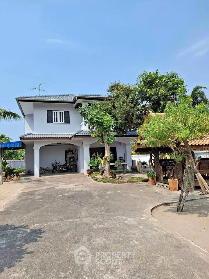 Charming two-story house with spacious driveway and lush greenery.
