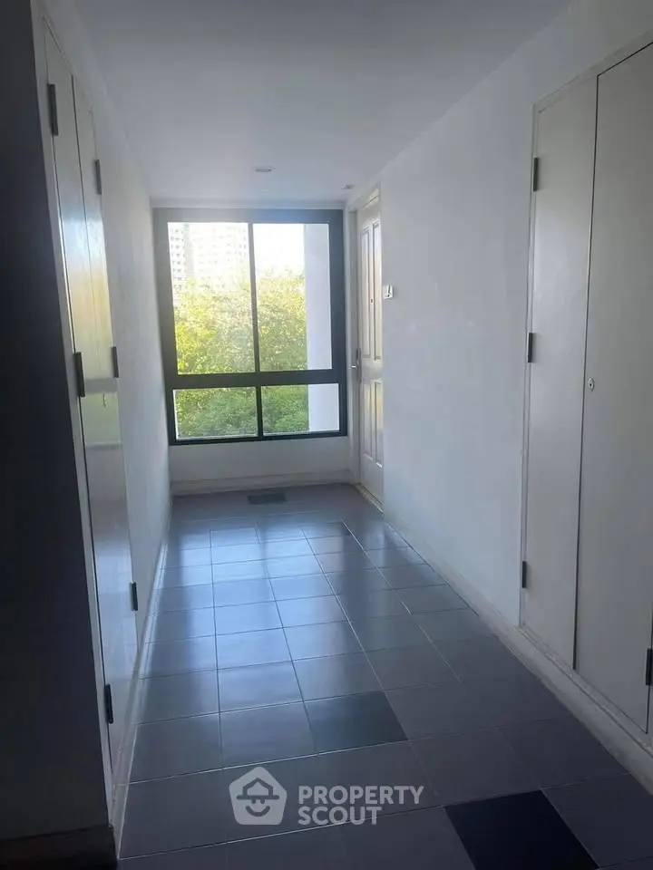 Bright corridor with large window offering a view of greenery and cityscape.