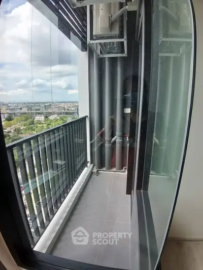 Modern high-rise apartment balcony with glass railing and city view.