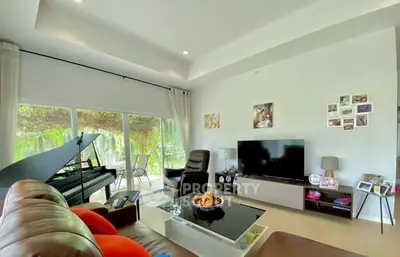 Spacious living room with modern decor and large windows overlooking greenery.