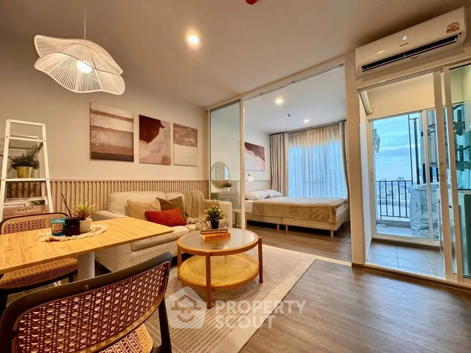 Modern open-plan living room with stylish decor and adjacent bedroom with balcony view.