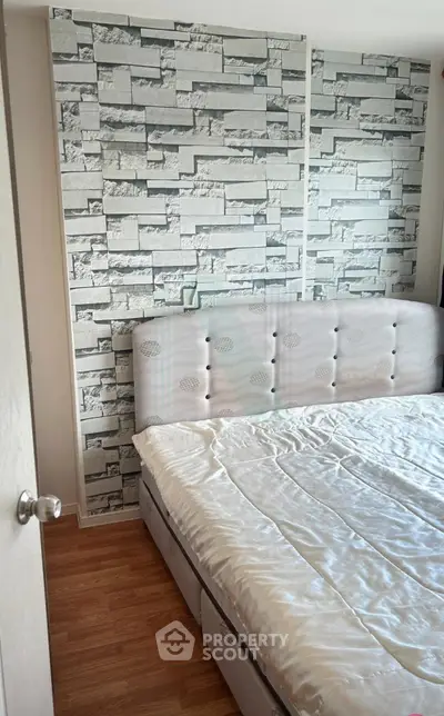 Modern bedroom with stylish stone accent wall and cozy bed