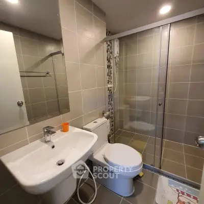 Modern bathroom with sleek design, featuring a glass-enclosed shower and contemporary fixtures.