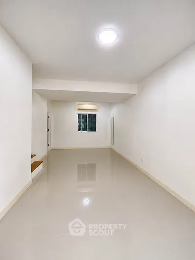 Spacious and bright living room with glossy tiled floors and modern lighting.
