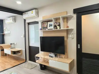 Modern living room with wall-mounted TV and stylish shelving in a cozy apartment.