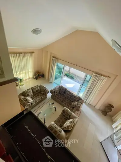 Spacious living room with high ceiling and large windows offering garden view