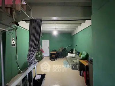 Cozy living room with green walls and loft area, featuring a comfortable sofa and dining table.