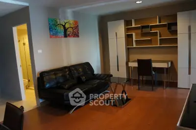Modern living room with sleek black leather sofa, stylish wall art, and contemporary shelving unit.