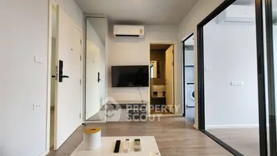 Modern living room with sleek design, wall-mounted TV, and air conditioning, adjacent to a compact bathroom.