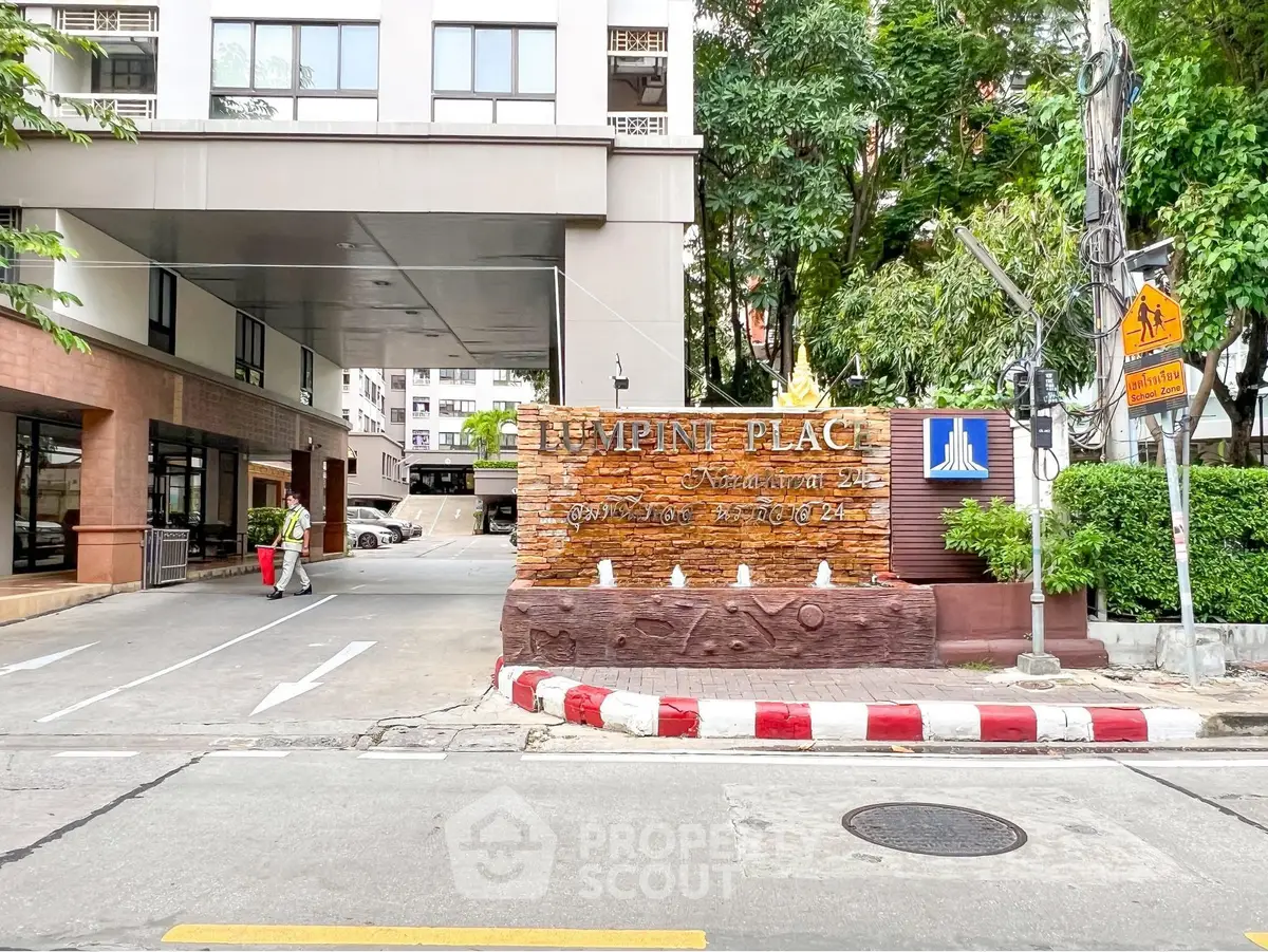 Modern building entrance with signage and lush greenery at Lumpini Place.