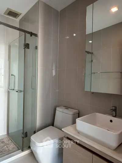 Modern bathroom with sleek fixtures and glass shower enclosure in a contemporary apartment.