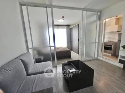 Modern apartment with sliding glass doors separating living room and bedroom, featuring sleek furniture.