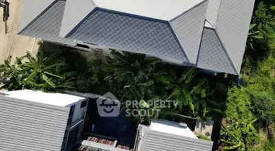 Aerial view of modern building with lush greenery and sleek roof design.