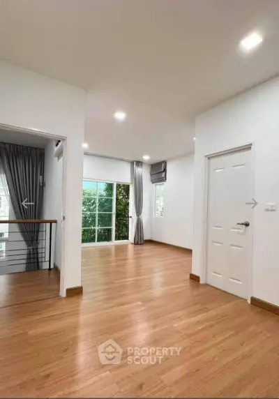 Spacious modern living room with wooden flooring and large windows for natural light.
