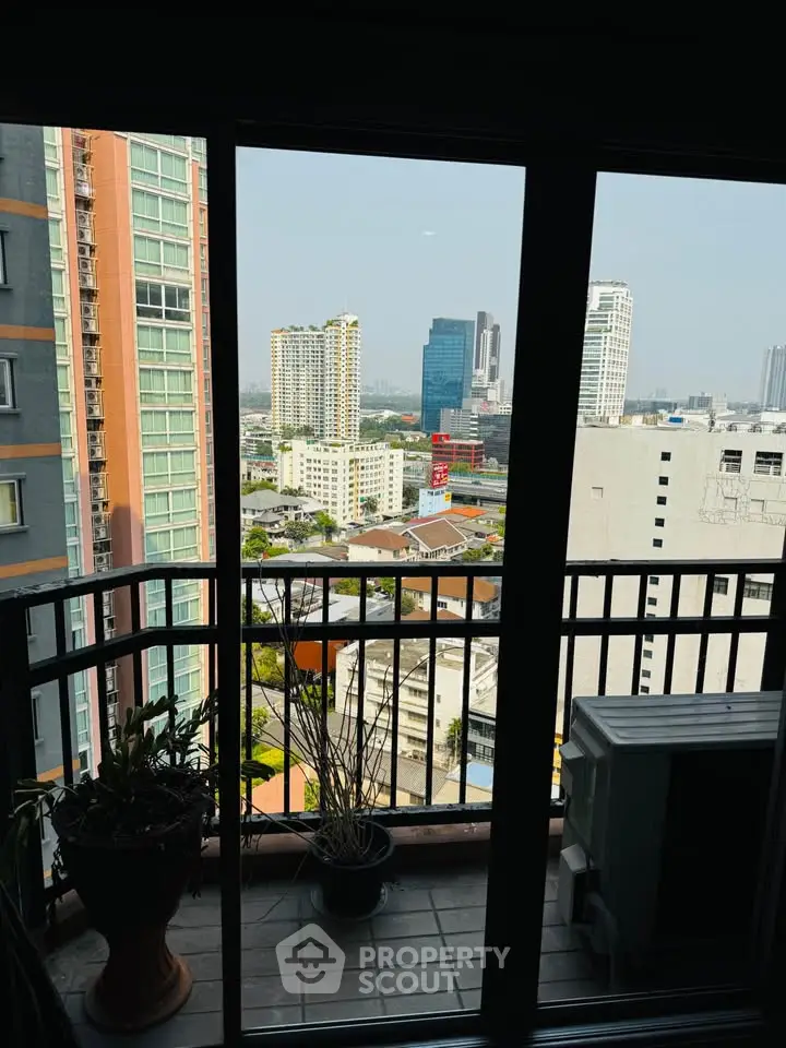 Stunning city view from a high-rise balcony with modern railing and potted plants.