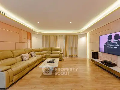Spacious modern living room with luxurious leather sectional and large TV, perfect for entertainment.