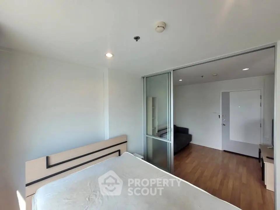 Modern bedroom with sliding glass doors and wooden flooring in a stylish apartment.