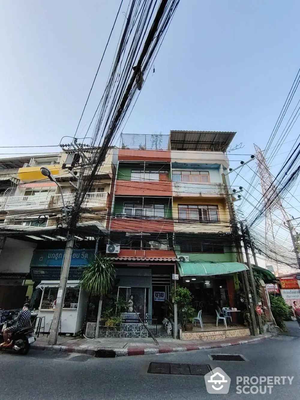 Vibrant multi-story commercial-residential building in a bustling urban area, featuring storefronts on the ground floor and living spaces above.