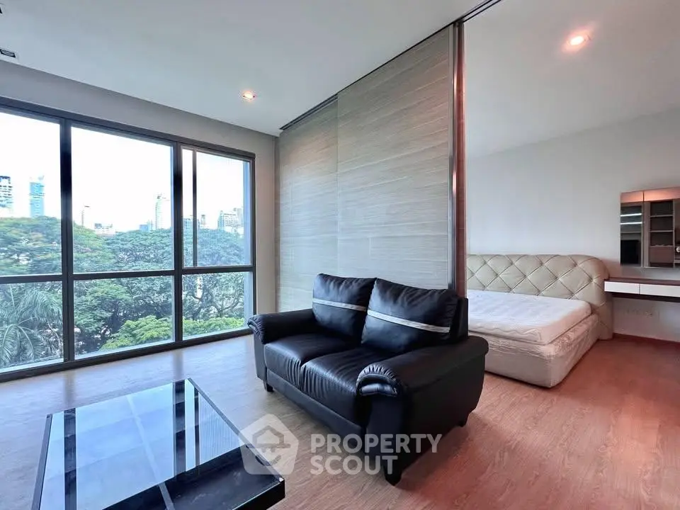 Modern studio apartment with large windows and city view, featuring a cozy living area and stylish bedroom.
