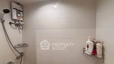 Modern bathroom with white tiles and shower heater, featuring sleek shower fixtures and toiletries.