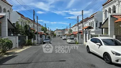 Charming residential street with white houses and red roofs under a clear blue sky.